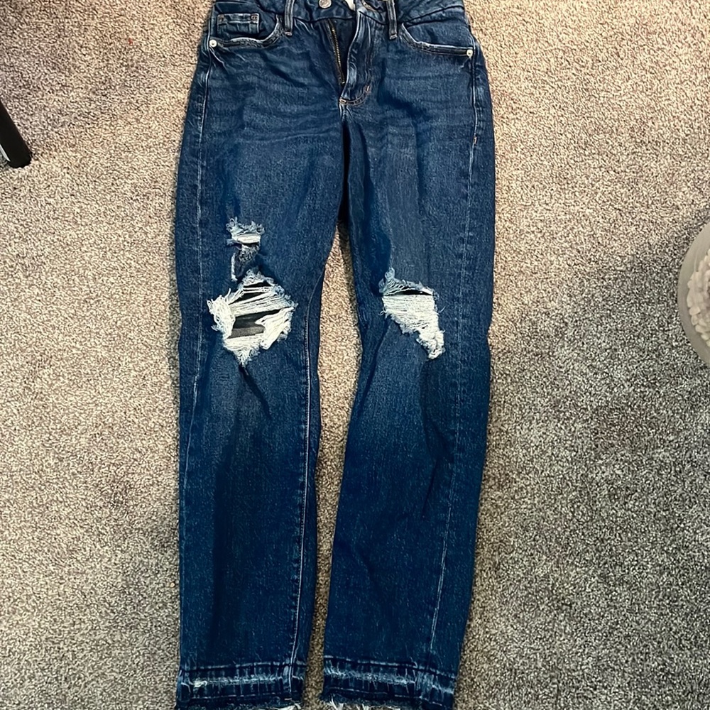Dark blue jeans with rips and blue string at the bottom